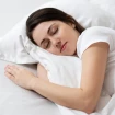Mujer durmiendo en una cama de sábanas blancas