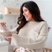 Isa Pantoja sonriente en la habitación de su futuro hijo con unos patucos en la mano
