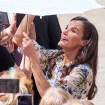 La reina Letizia mirando la sombrilla de una señora.