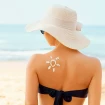 Mujer tomando el sol con una pamela y un sol de crema solar pintado en el hombro.