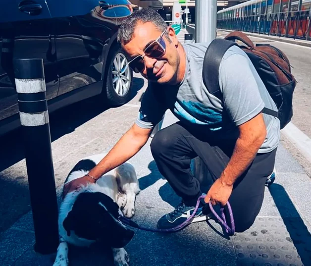 Jorge Javier posando junto a un perro en la calle.
