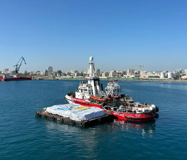 Barco de Open Arms junto a un cargamento de ayuda humanitaria.