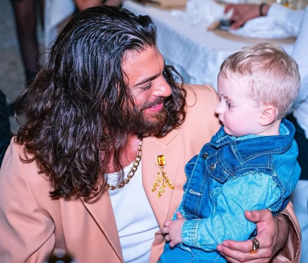 Can Yaman con un niño pequeño en brazos.