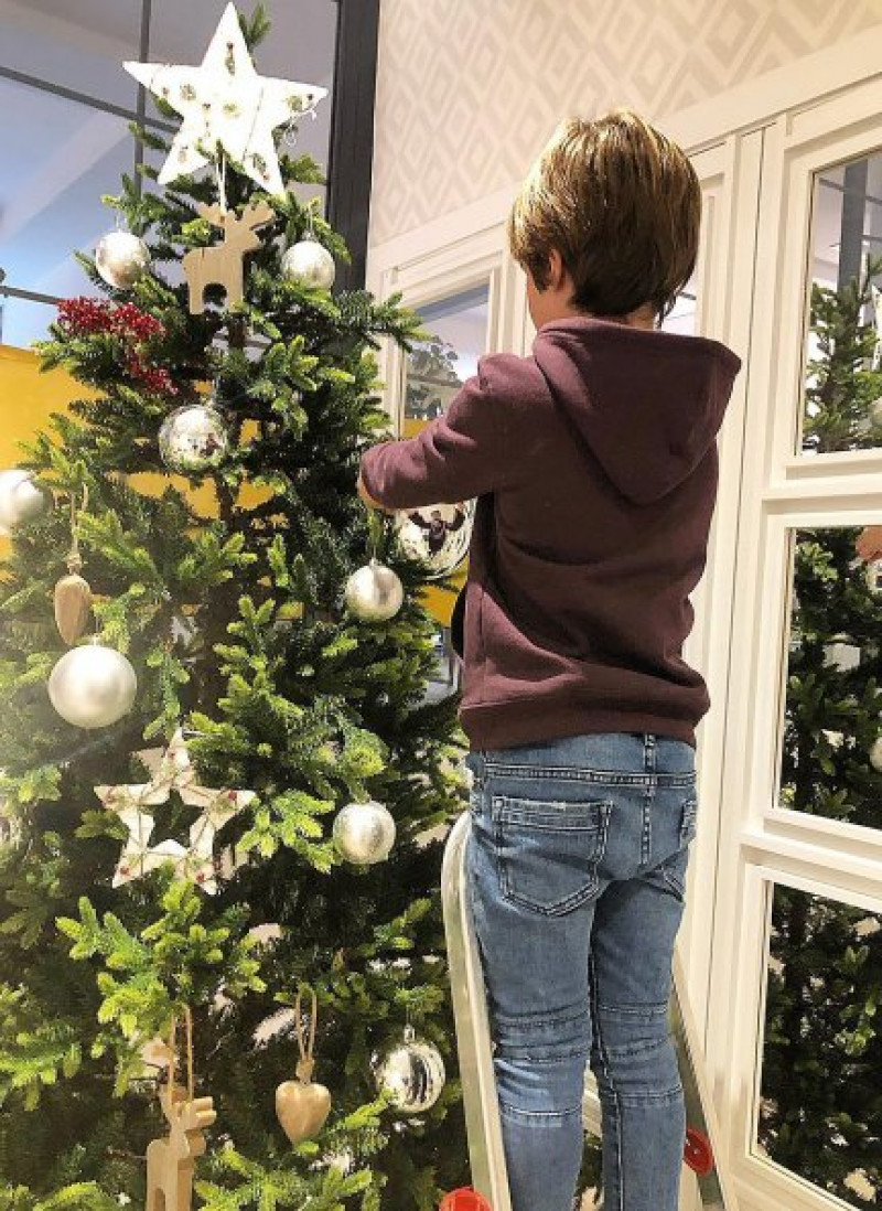 Un hijo de Amelia Bono pone una bola en el árbol.