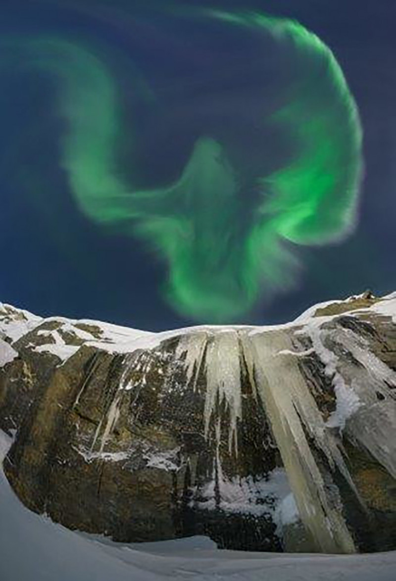 Lo que más llama la atención de esta aurora boreal es su extraña forma de águila, imponente sobre la montaña nevada.