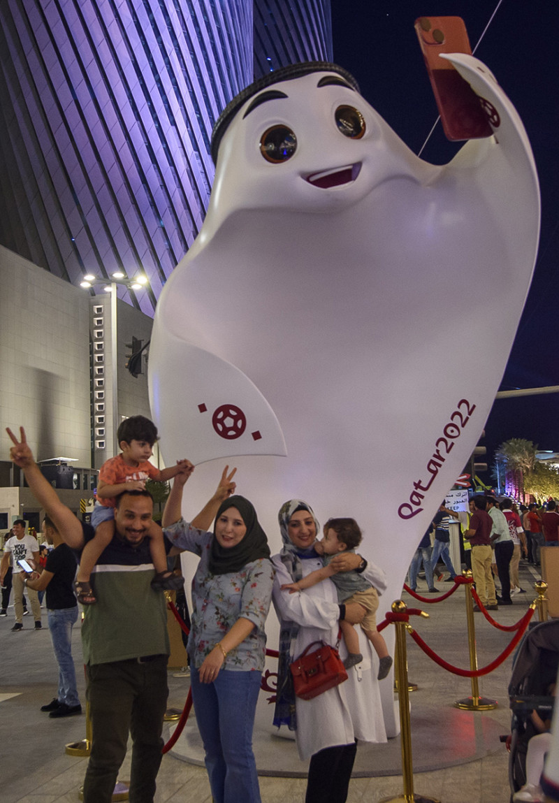 Una familia se toma una foto junto a la mascota del mundial de Catar