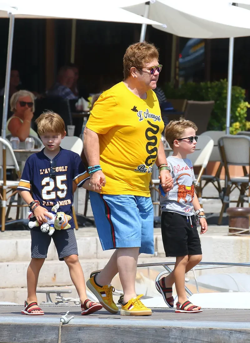 Elton John paseando con sus hijos cogidos de la mano.
