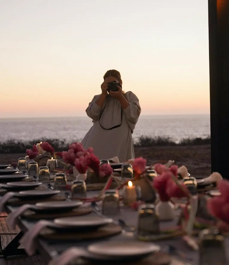Alejandra Silva tomando una foto de una mesa de banquete junto a una playa.