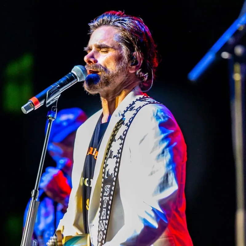 John Stamos en una imagen tocando la guitarra sobre el escenario