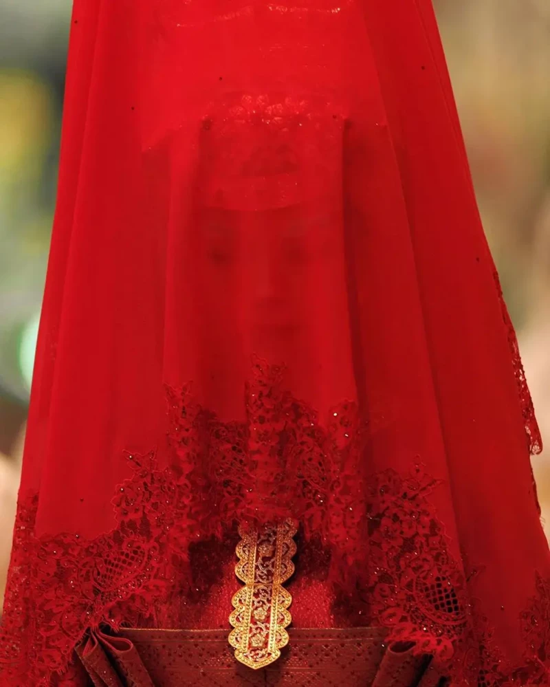 La novia bajo un velo ceremonial rojo.