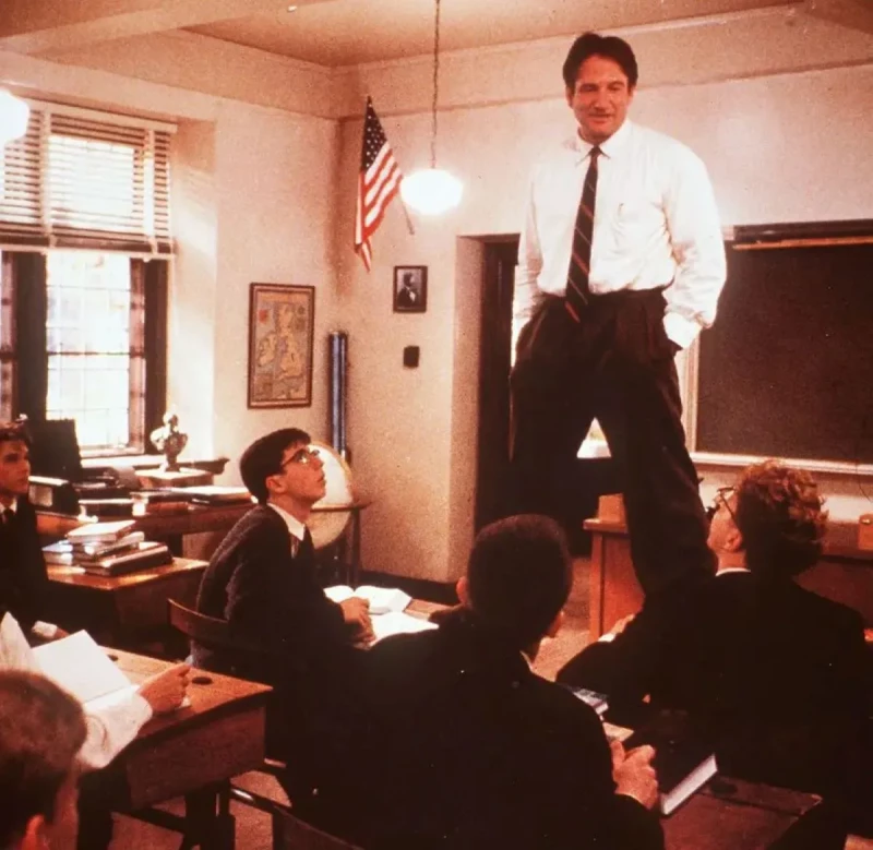 Robin Williams, en una de sus actuaciones, subido a uno de los pupitres de una clase.