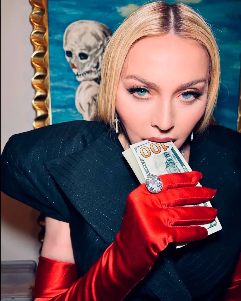 Madonna posando con un fajo de billetes sobre los labios.