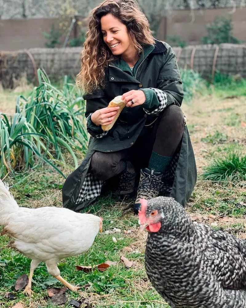 Laura Madrueño con algunas de las gallinas que cría en su casa, una vivienda rústica y sostenible en plena Sierra de Madrid.