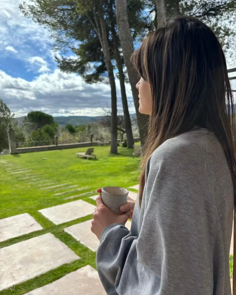 Isabel Jiménez tomando una bebida y mirando al campo.