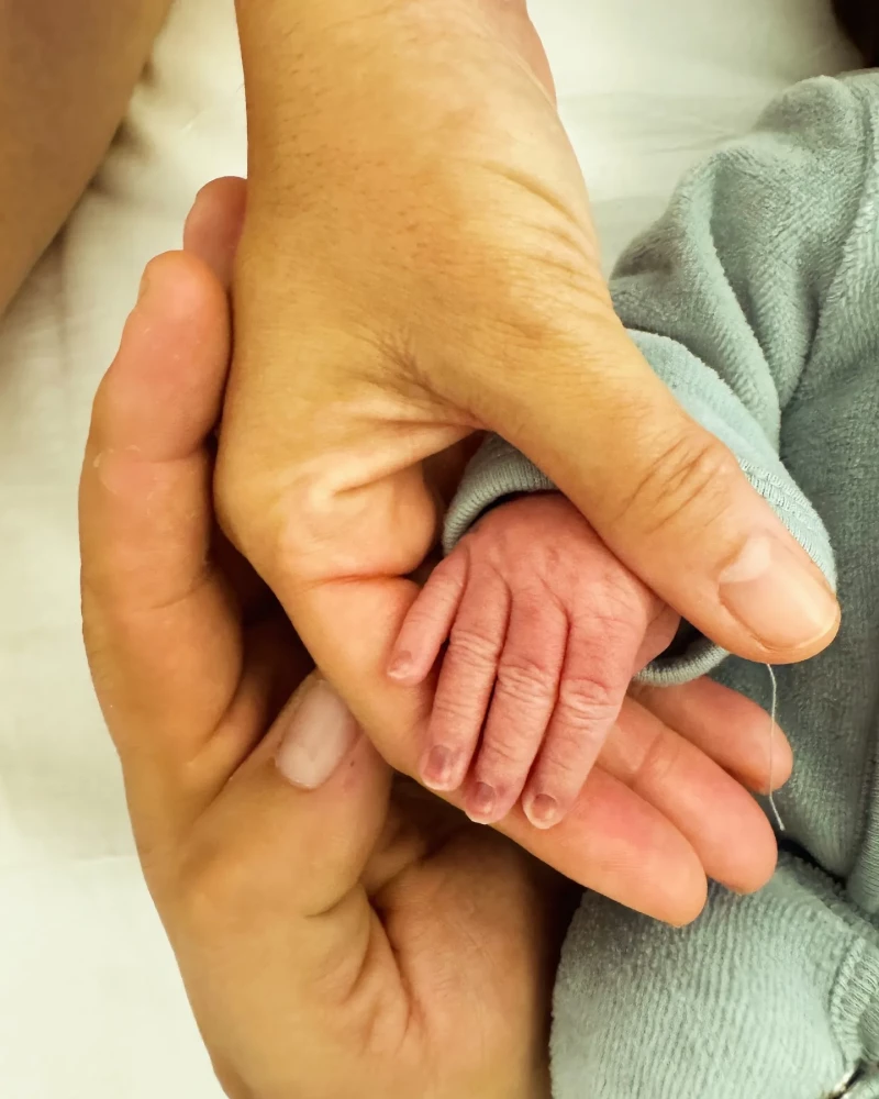 Gisela sujeta la mano de su bebé, Indiana.