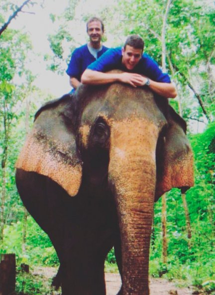 Padre e hijo, divertidos, subidos a un elefante.