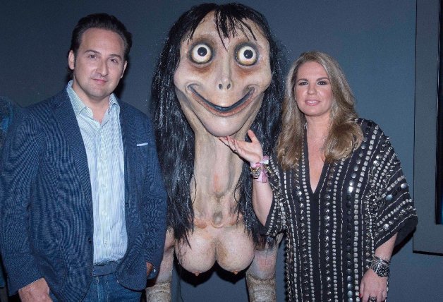 Íker Jiménez y Carmen Porter junto a una reproducción de 'Momo Challenge' en la exposición 'Cuarto Milenio: una historia de miedo'.