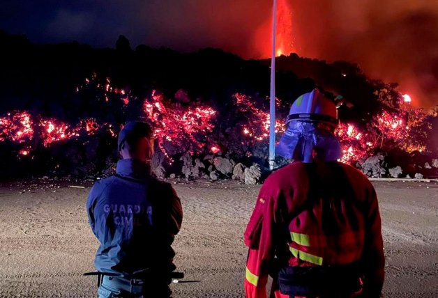 Un guardia civil y un bombero observan, impotentes, el avance lento e inexorable de la lava, que tiene más de 1.000 grados de temperatura.