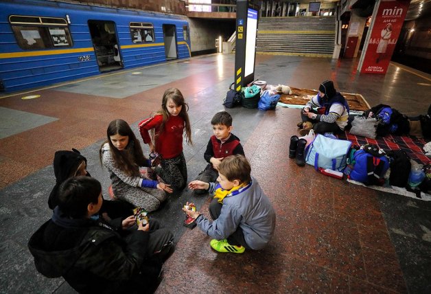 Varios niños ucranianos esperan en el metro a que termine el bombardeo.