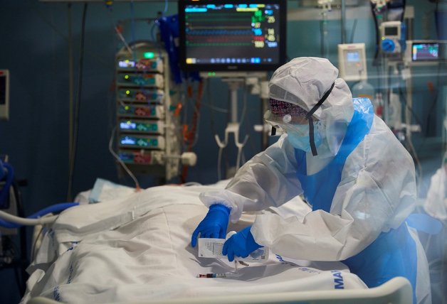 Un sanitario, con el equipo de protección, ocupándose de un paciente.