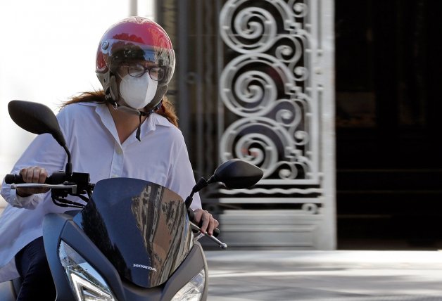 Una motorista en una calle de Valencia se protege con mascarilla.