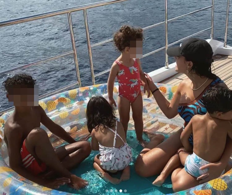 Georgina con sus hijos se refrescan todos juntos en una piscina hinchable.