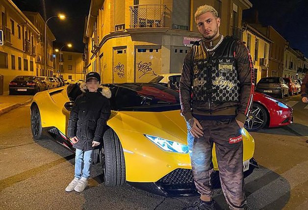 Omar e hijo posando en un Lamborghini amarillo.