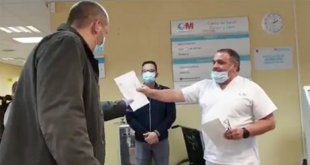 Un trabajador del hospital entrega una dedicatoria de agradecimiento al taxista.