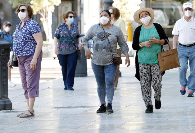 Un grupo de personas pasea por la calle con mascarilla.