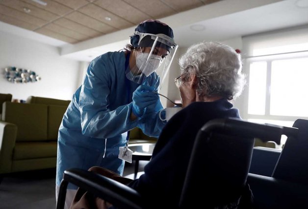 Una cuidadora da de comer a una anciana en una residencia.