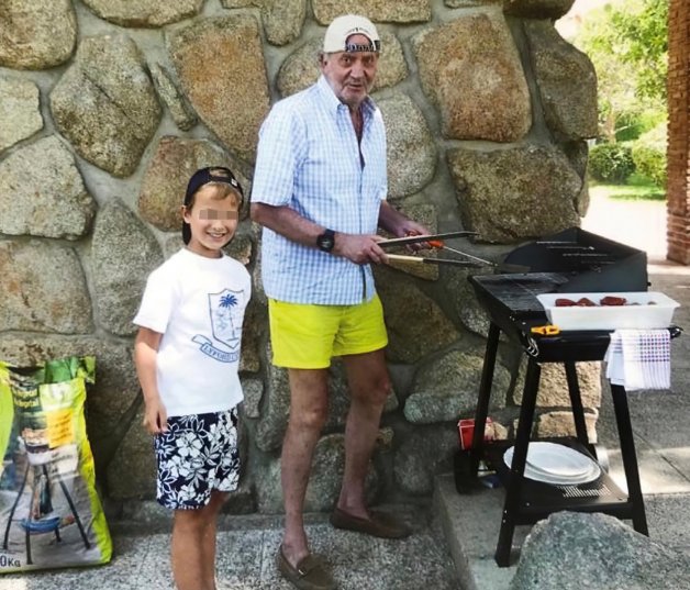 El rey emérito haciendo una barbacoa, con Alexander a su lado.