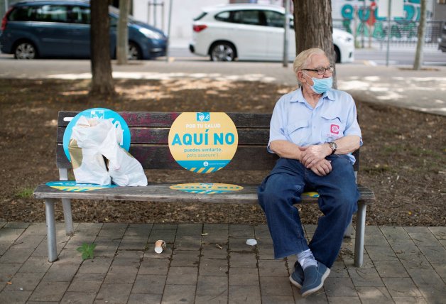 Un hombre descansa en un banco de Barcelona.