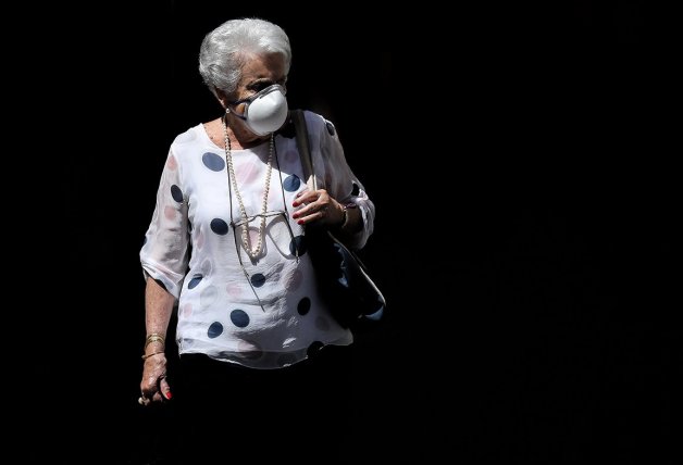 Una mujer pasea protegida con una mascarilla.