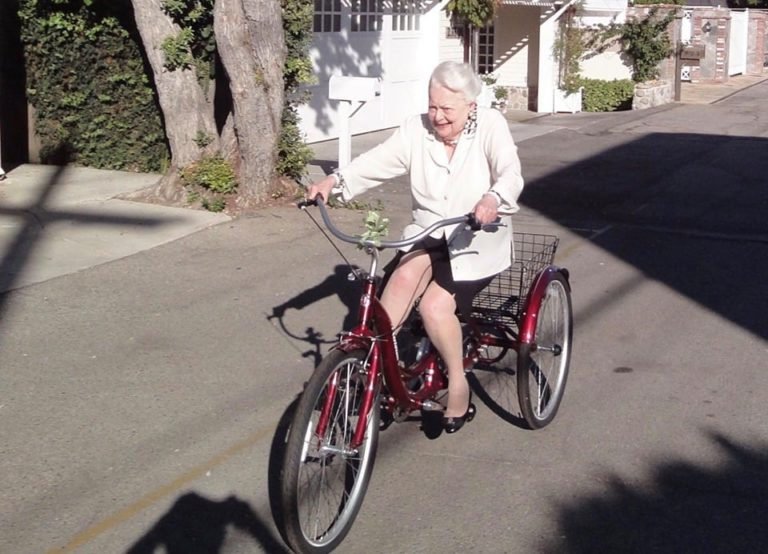 Olivia de Havilland llevando un triciclo con 102 años por las calles de París.
