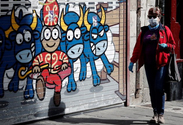 Una mujer camina por una calle de Pamplona junto a un grafiti de los Sanfermines.