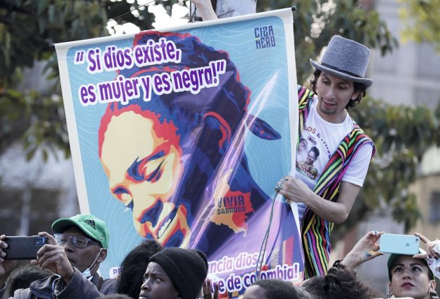 Un joven, con una pancarta en un acto electoral.