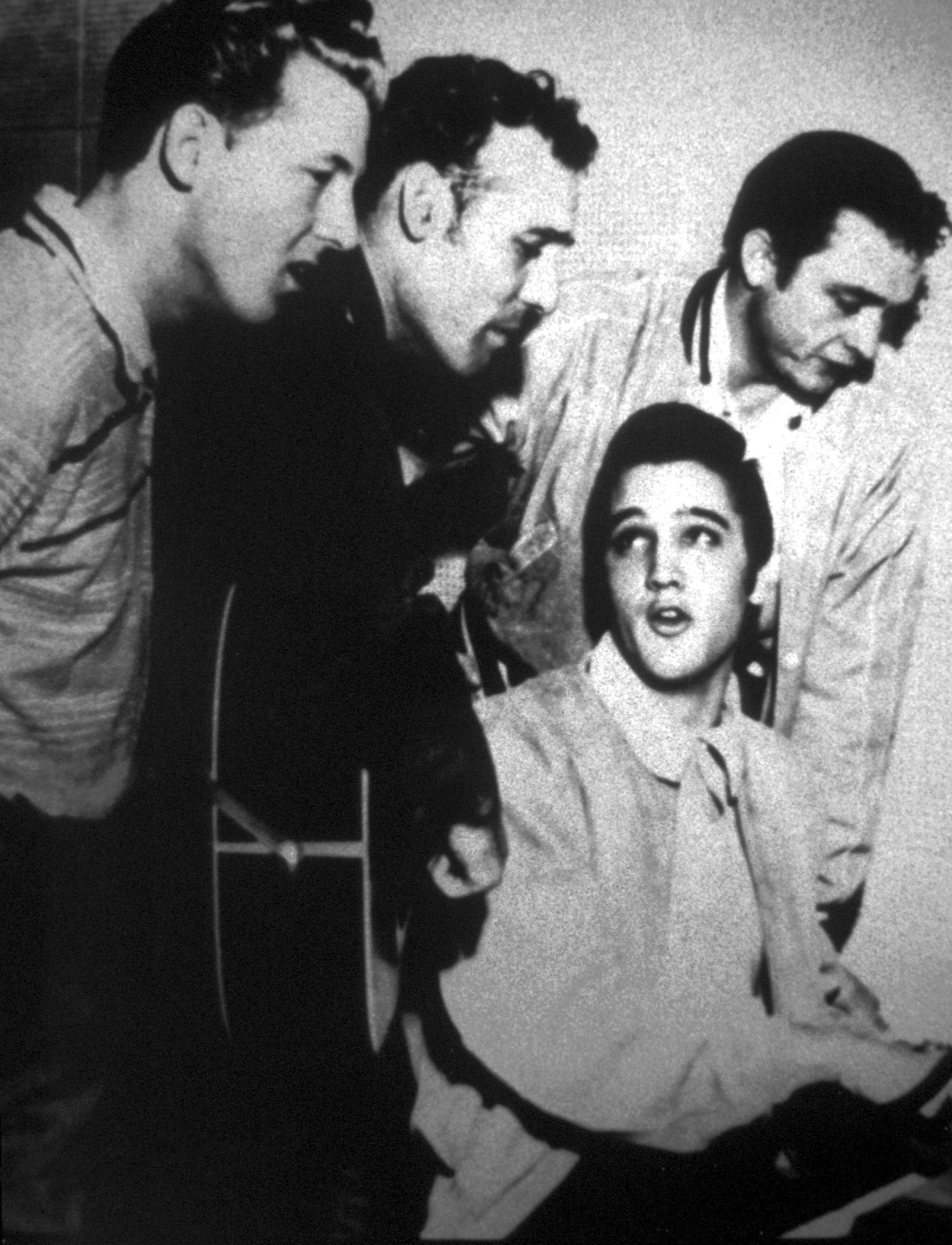 Imagen del cantante Elvis Presley sentado, cantando junto a Jerry Lee Lewis (izda.), Carl Perkins (con guitarra) y Johnny Cash (dcha.).