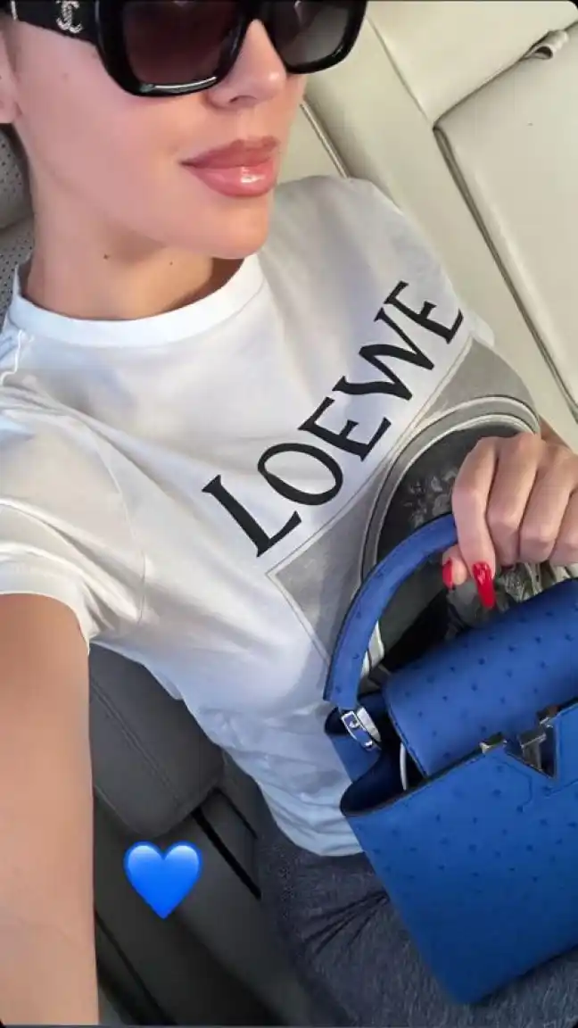 Georgina Rodríguez en su jet con una camiseta de Loewe blanca y un bolso azul de Louis Vuitton