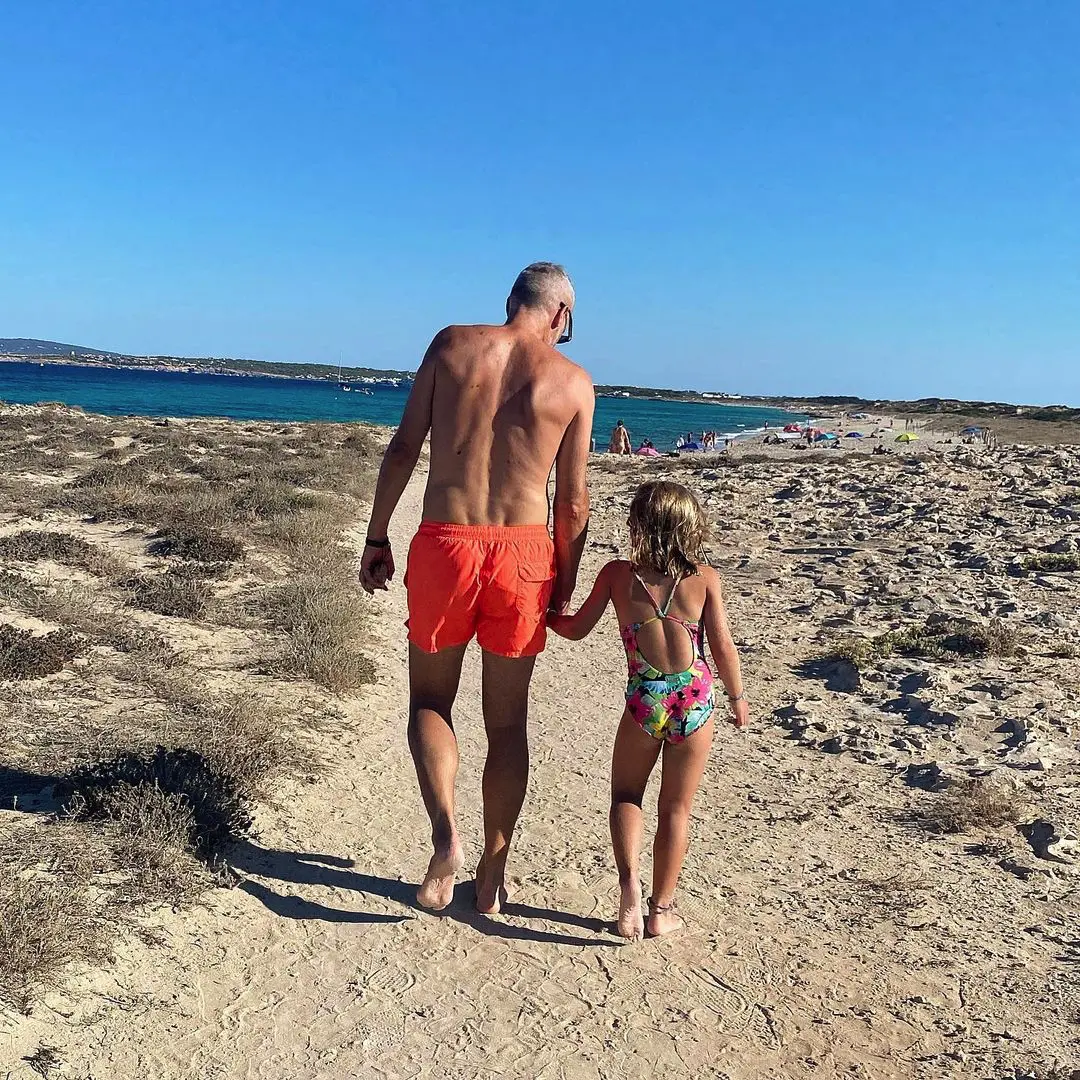 Álex Corretja con su hija pequeña, caminando en la playa