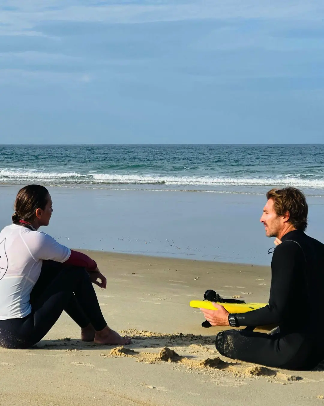 Mar Flores en la playa con su instructor de surf