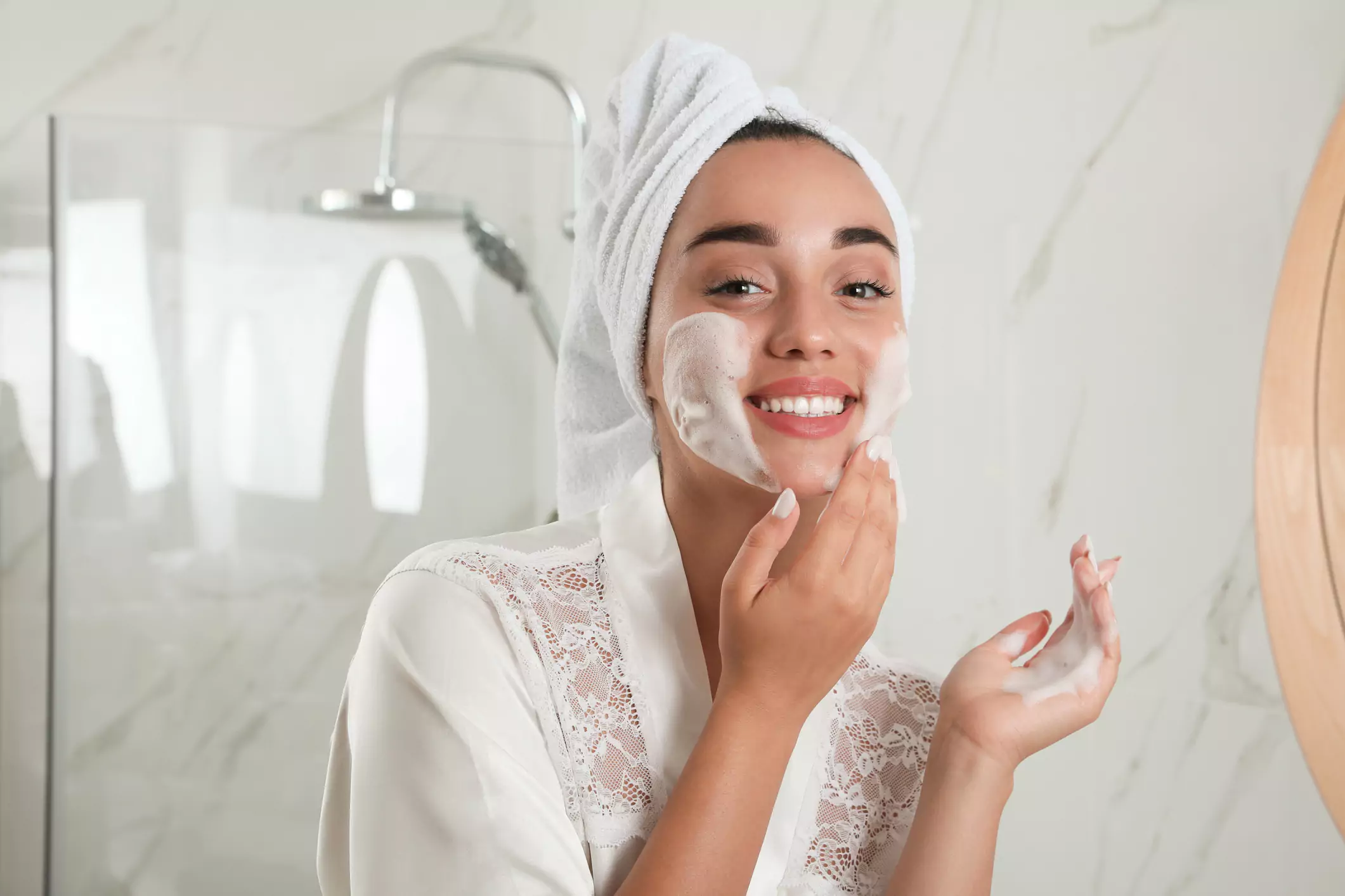 Mujer joven que aplica espuma limpiadora para cuidado de la piel