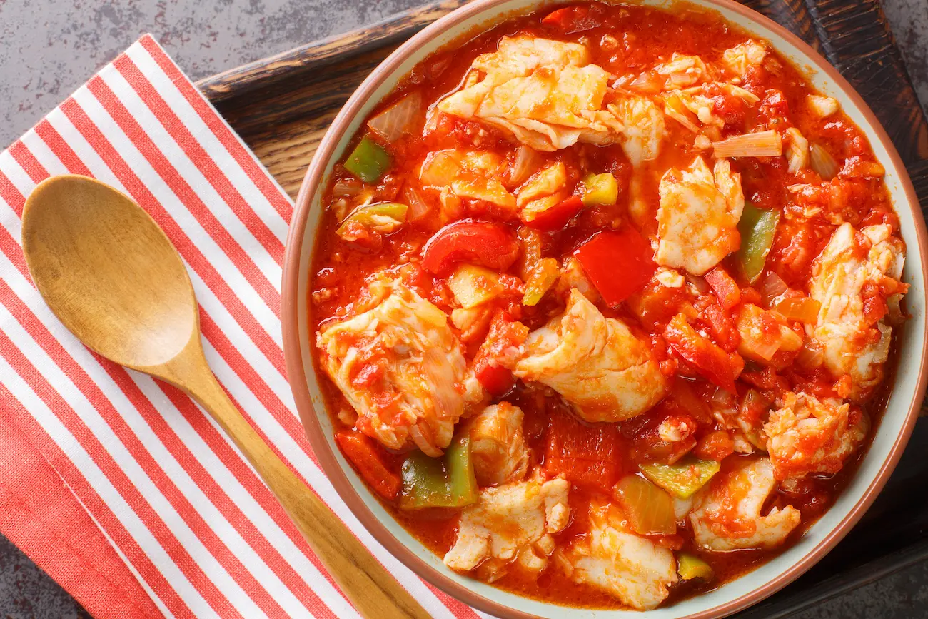 Bacalao al ajoarriero Bacalao con pimientos y salsa de tomate en primer plano sobre el bol. Vista superior horizontal - Foto de stock