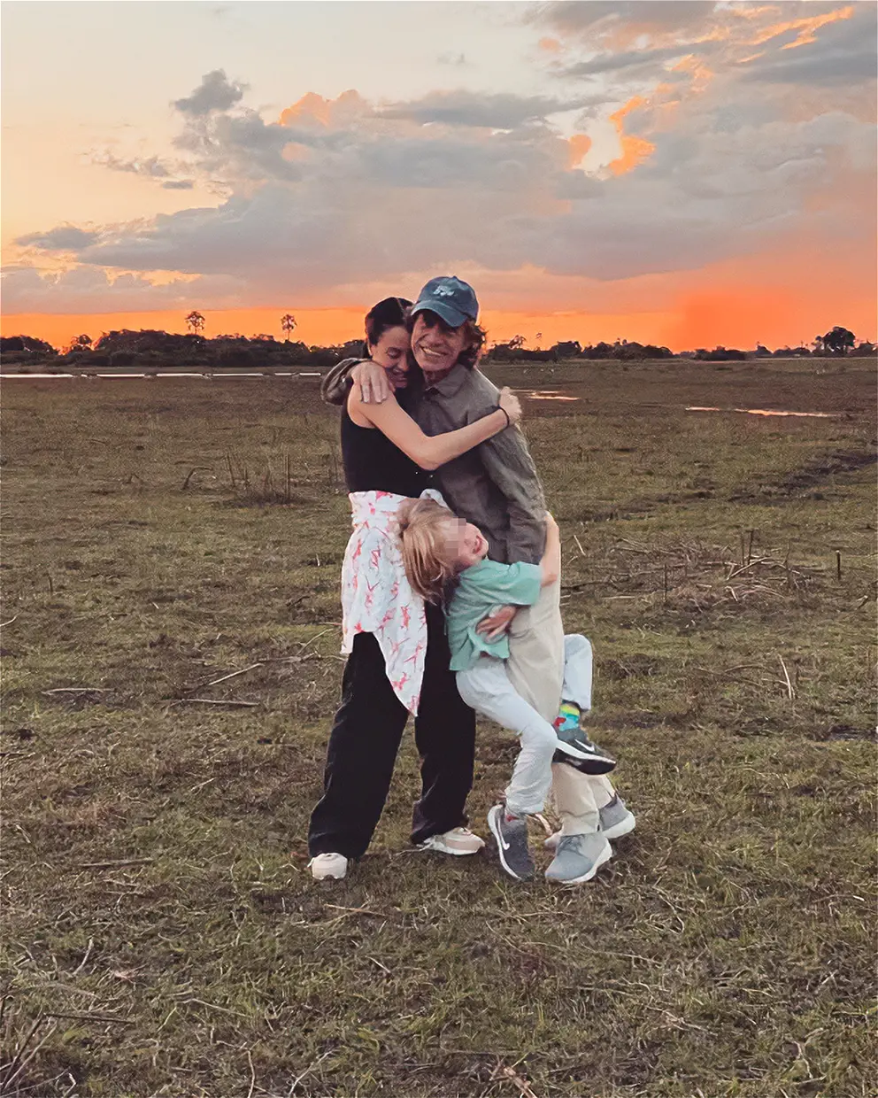 Mick Jagger posando abrazado a su novia y su hijo