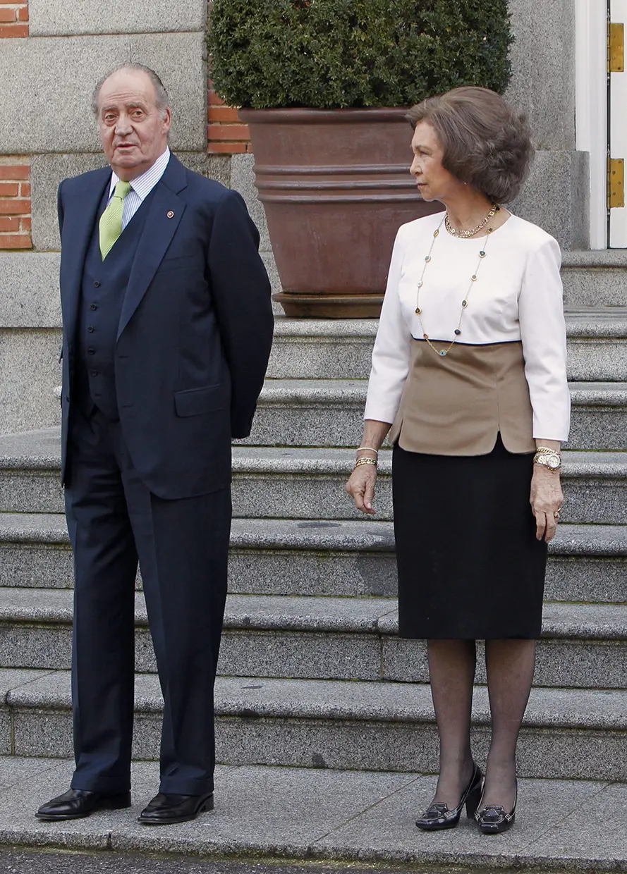 El rey Juan Carlos I y la reina Sofía posando separados ante unas escaleras.