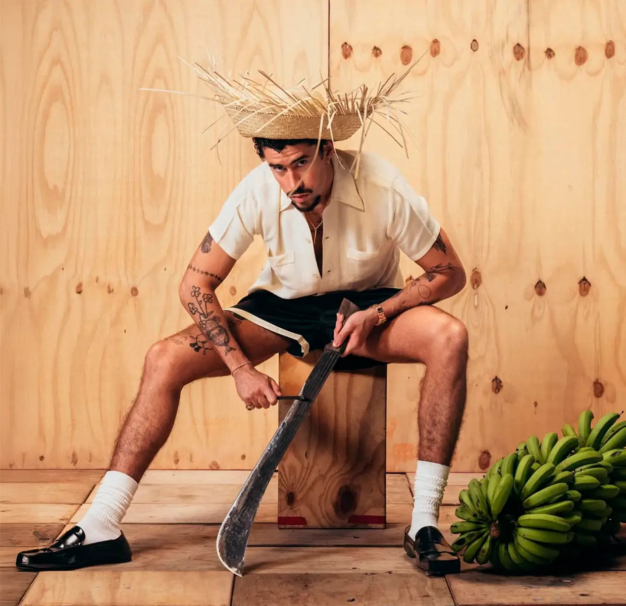Bad Bunny con un machete y un sombrero de paja junto a unos plátanos.