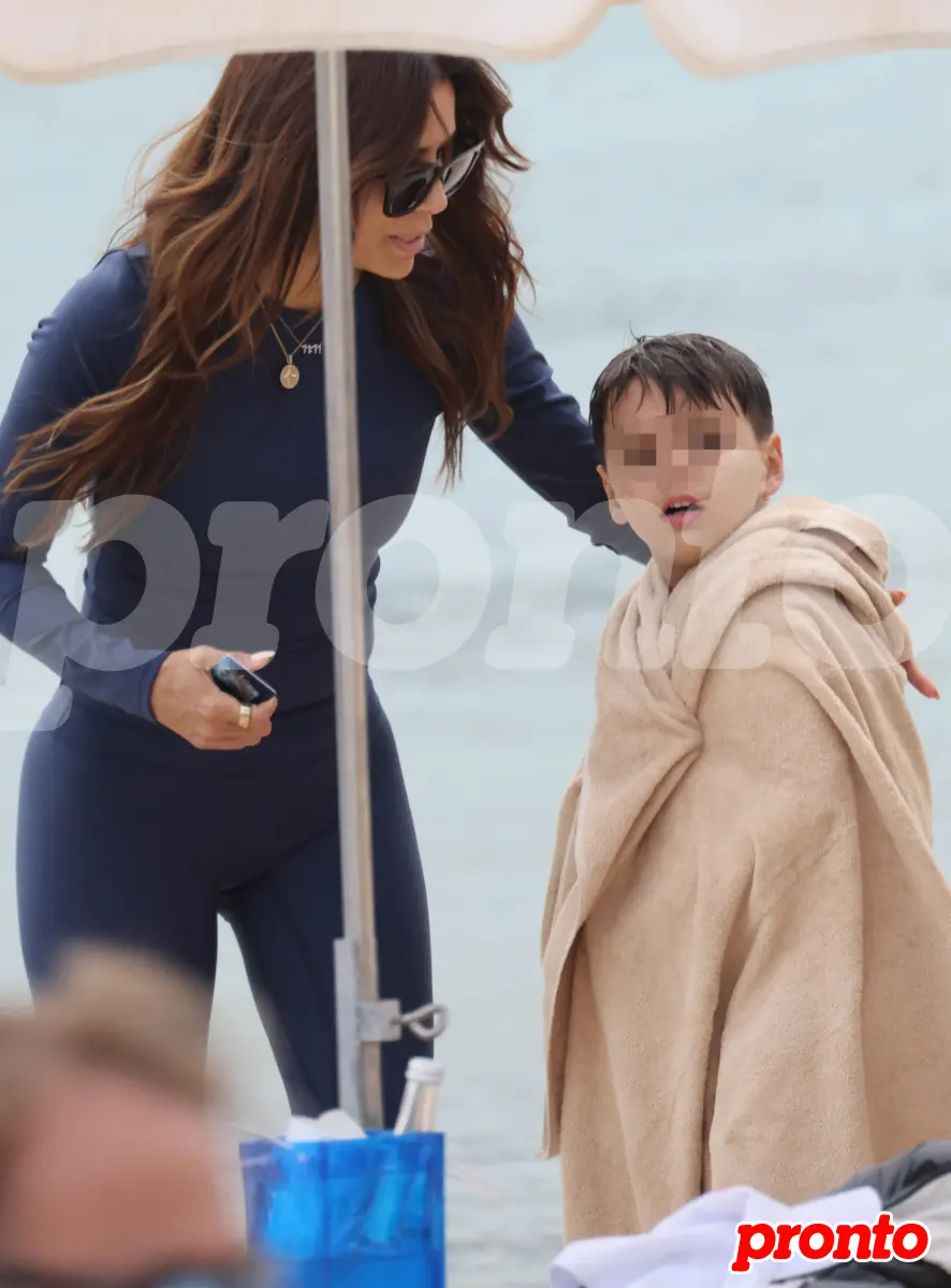 Eva Longoria con su hijo envuelto en una toalla junto al mar.