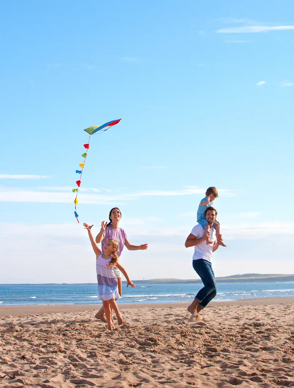 Familia jugando con una cometa en la playa
