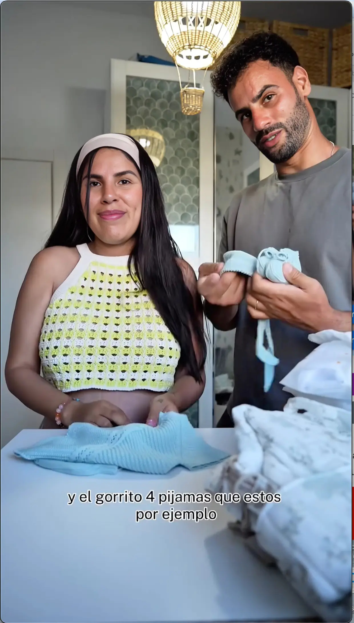 Isa Pantoja y Asraf Beno mostrando los patucos de su futuro bebé.