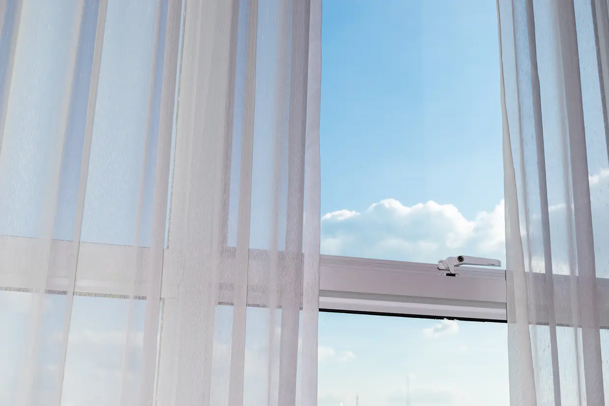Ventana con cortinas que dejan ver un cielo azul