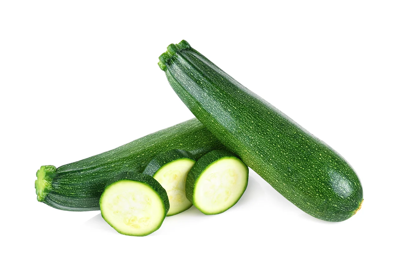 Calabacín fresco entero y en rodajas, ingrediente saludable para aligerar el estofado de guisantes y brócoli